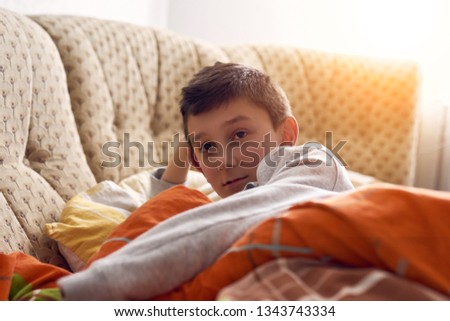 little boy lying on the bed and watching TV