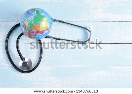 Stethoscope and globe on blue and white pastel wooden background. Save the world, Global healthcare, Green Earth day concept and World Health Day concept.