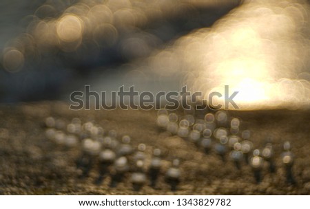 Blur of chess pieces on a brown rock with sunset sea in background at twilight time