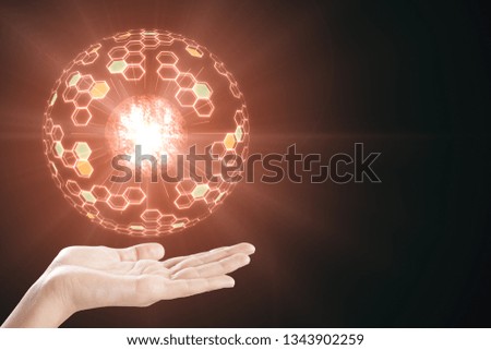 Hand holding abstract glowing sphere on dark background. Innovation and technology concept