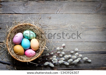 Easter colorful eggs in the nest with flowers on vintage wooden boards and empty space