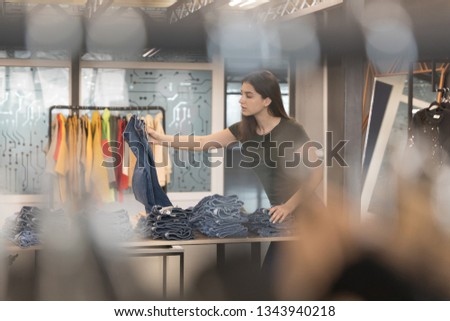 Young brunette girl chooses his jeans in the store.