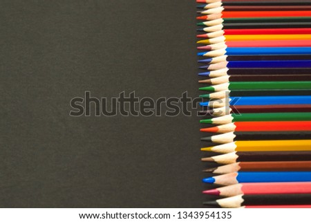 Colored pencils lined in a row on a black background background