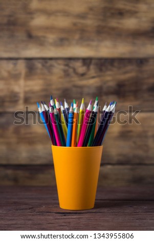 Color Pencils In Orange Grocery on Wooden Background