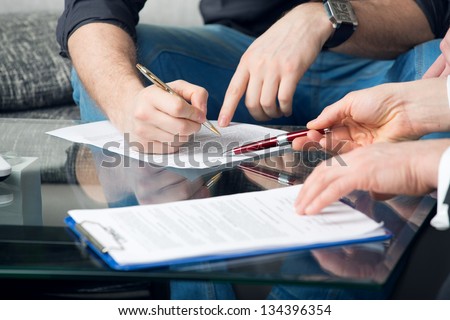Hands of two men signed the document, sitting at the desk
