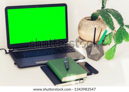 Green screen laptop, cactus plant in clay pot, book, notebook, smartphone. Workplace at home during the pandemic. The quarantine concept of stay home stop coronavirus COVID-19 spreading.