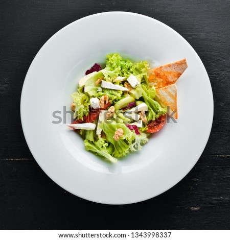 Vegetable salad with cheese, olives and cherry tomatoes. In the plate. Top view. Free space for your text. Rustic style.