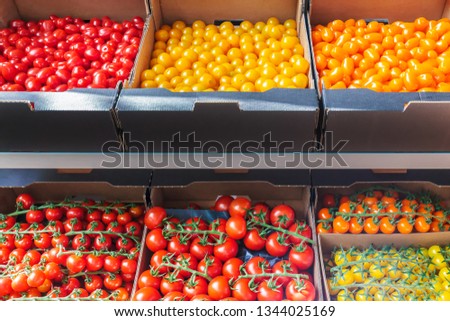 Retail display of diverse fresh yellow, orange and red tomatoes in crates Royalty-Free Stock Photo #1344025169