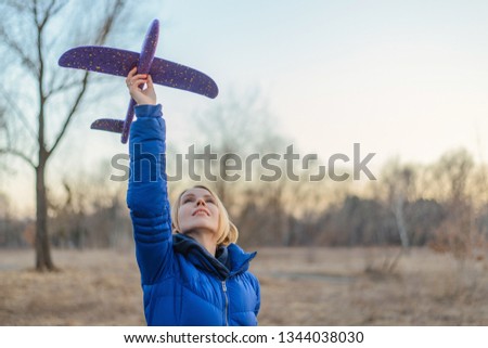 A woman launches a toy plane in nature.