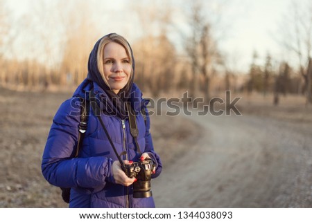 A woman photographer holds a camera in her hands. The concept of a woman photojournalist.