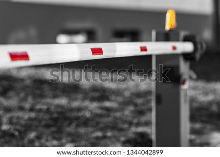 Automatic barrier white and red. The barrier is closed. The background is blurred. Shallow depth of field.