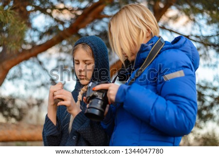 Mom shows her daughter pictures on the camera in the forest.