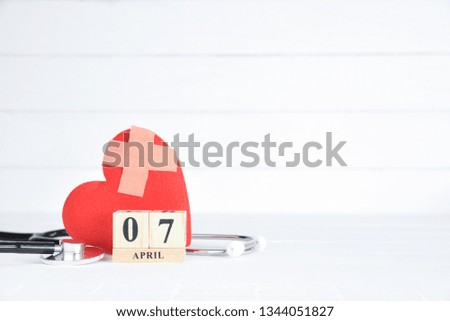 Stethoscope and Red heart with April 7 text wooden block calendar on white wooden background. World Health Day concept.