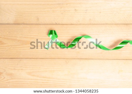 Green ribbon on the wooden table with space for copyspace. Health day concept