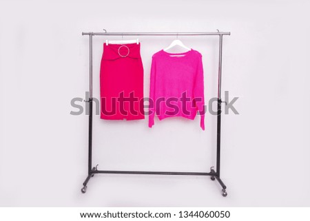 Pink sweater with red skirt with on hanger
