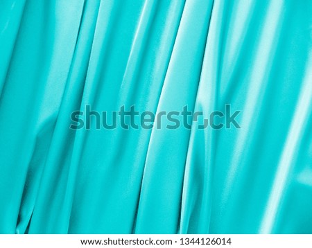 Smooth elegant wavy turquoise satin silk luxury cloth fabric texture, abstract background design. Card, banner or invitation.
