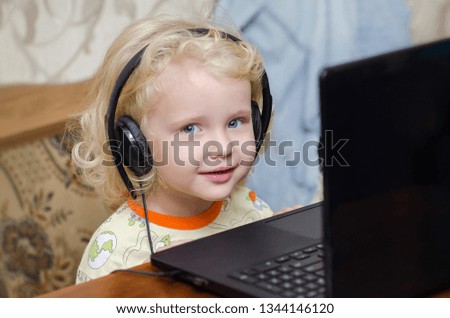 Childhood and gadgets. Curly blondy little girl with headphones. Technology and people concept. Damage of headphones  on child`s hearing 