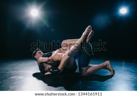 mma fighter doing chokehold and joint lock to another sportsman during submission wrestling