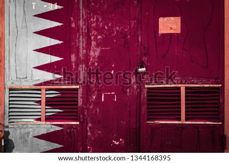 Close-up of old warehouse gate with national flag of Qatar. Concept of Qatar export-import, storage of goods and national delivery of goods. Flag in grunge style
