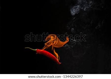 Red chilli with flame, black background, the concept of spicy - pictures
