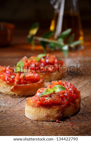 Colourful red tomato bruschetta on slices of crisp crusty toasted or grilled baguette lying on an old grunge badly scored wooden chopping board, low angle view with copyspace