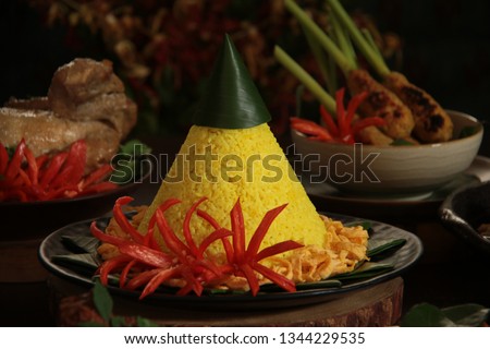 Nasi Tumpeng Kuning. The yellow rice in cone shape; a festive Indonesian rice dish presentation. Royalty-Free Stock Photo #1344229535