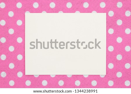 Blank beige greeting card on pink and white polka dot fabric that you can use as a mock up for your message