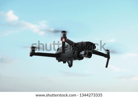 Professional filming drone flies in the air at a low altitude against a blue sky. Drone makes photos. Modern new technology. Ready background with place for your text.