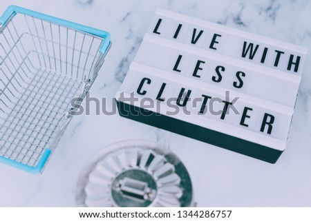 ecology and consumerism concept: live with less clutter message on lightbox with shopping basket and trash bin