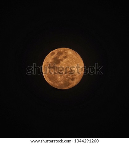 The full moon is orange in the sky.