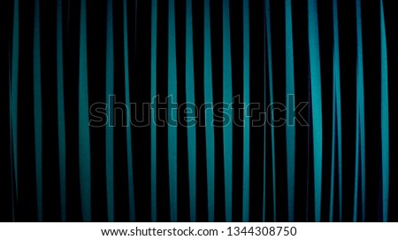 Close-up photo of louvers on windows in darkness. Modern architecture or interior fragment with contrast lights and shadows. Toned abstract architectural background with angles and parallel lines.