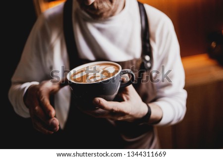 A good day starts with coffee! Top view image of barista holding cup of fresh coffee, coffee shop worker serving cappuccino, beautiful latte art Rosetta pattern 