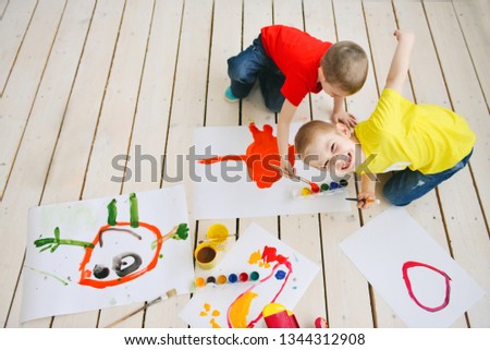 naughty creative children paint brush paints on paper funny colorful pictures on a wooden floor, art in a group art school. in a creative search for emotion