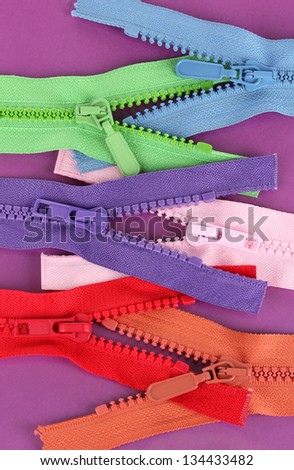 Multicolored zippers on purple background
