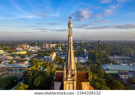 Aerial view of the famous Cai Be church in the Mekong Delta, Roman architectural style. In front is Cai Be floating market on Tien Giang river, Vietnam. Bell tower with the statue of Blessed Mother