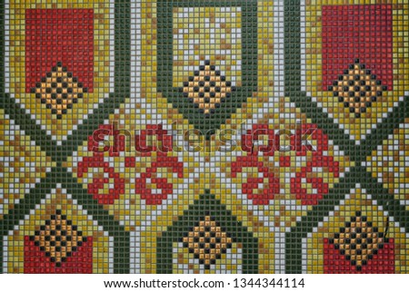 Close up of geometric and floral pattern of green,yellow,red and white ceramic tiles.