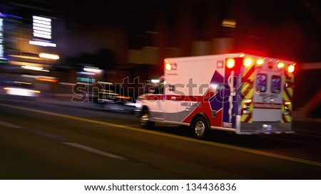 An ambulance speeding through traffic at nighttime Royalty-Free Stock Photo #134436836