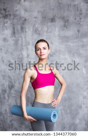 Portrait of cheerful woman holding exercise mat indoors. Workout fitness or yoga.