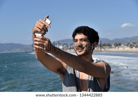 Carefree, handsome young man taking a selfie with a smart phone at a tropical resort