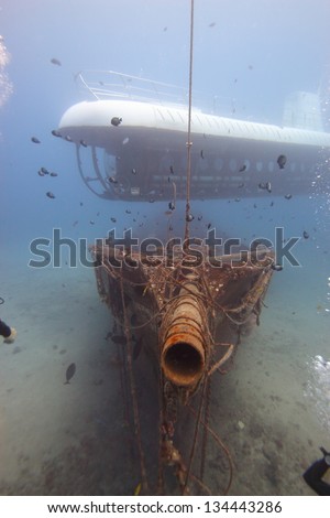 Modern and Ancient: A submarine hovers above an old ship wreck.