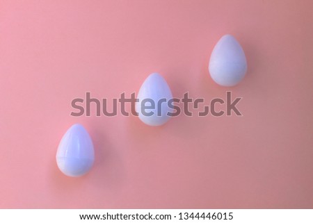 White eggs on the background in pink pastel color. Three small plastic toy eggs. Kids toys. Minimalism food concept. Easter concept.