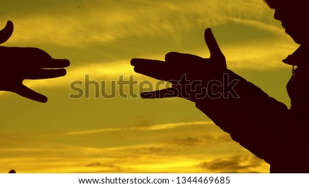 Children make shape of dog shape with hands at sunset. girls hold the gesture of a dog symbol with their fingers against sky. children show with hands the silhouette of an animal. shadow play