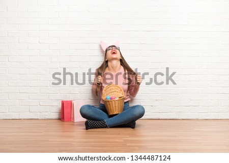 Woman with bunny ears for Easter holidays sitting on the floor annoyed angry in furious gesture