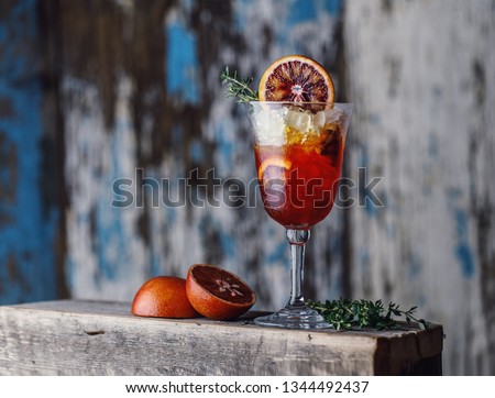 Fresh summer cocktail with red oranges in a glass on rustic background. Fresh  cocktail. Cocktail with gradient