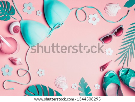 Female beach accessories on pink background, top view. Flat lay turquoise bikini, sunglasses, sandals with cocktail , seashells , tropical palm leaves. Summer holiday vacation layout. Frame