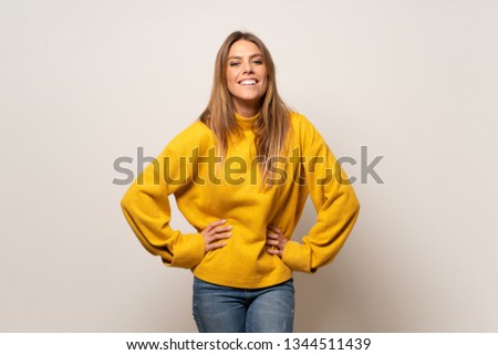Woman with yellow sweater over isolated wall smiling