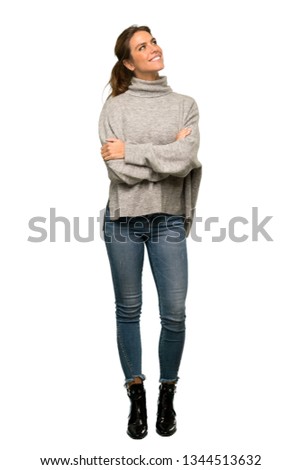 A full-length shot of a Blonde woman with turtleneck looking up while smiling over isolated white background