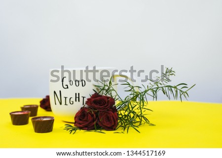 Coffee mug with bouquet of flowers and chocolate. Notes good morning on yellow table from above, beautiful breakfast, top view, flat lay