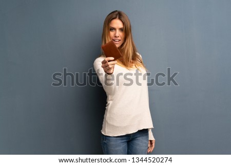 Blonde woman over grey background holding a wallet