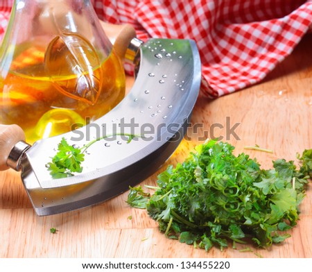 Modern herb cutter (wiegemesser) with wooden handles and a clump of flat head parsley.